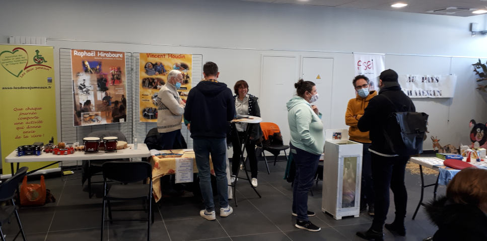 Stand de l'association avec 3 grandes affiches, des instruments de percussions plusieurs personnes dont une regarde les videos