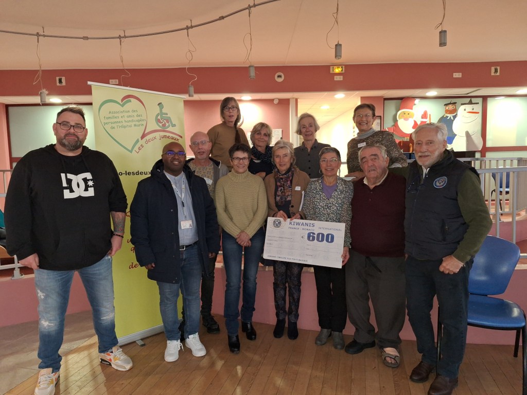 un groupe de personnes remercie les kiwanis qui offrent un cheque de 600 euros à l'association. 1 musicien, 3 personnes de l'Hôpital Marin de Hendaye, 3 personnes des Kiwanis, 4 autres membres des deux jumeaux. Salle hôpital Marin Rotonde