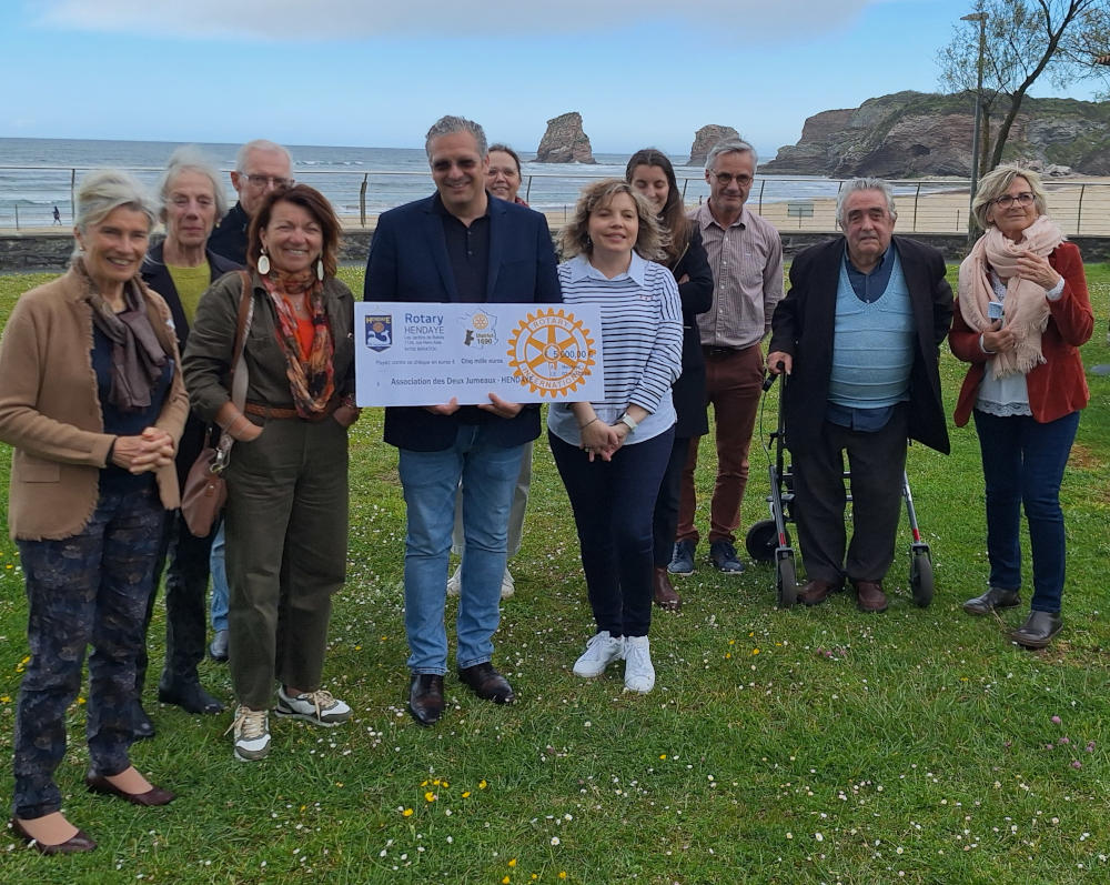 En extérieur au fond les rochers "deux jumeaux" de hendaye et un groupe de personnes du Rotary d'Hendaye, de l'Hôpital Marin et de l'association Les deux jumeaux et un grand chèque de 5000 euros