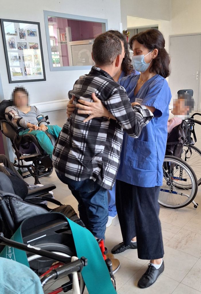 avec l'aide d'une aide soignante, la danseuse accompagne un patient à se mettre debout et va danser avec lui